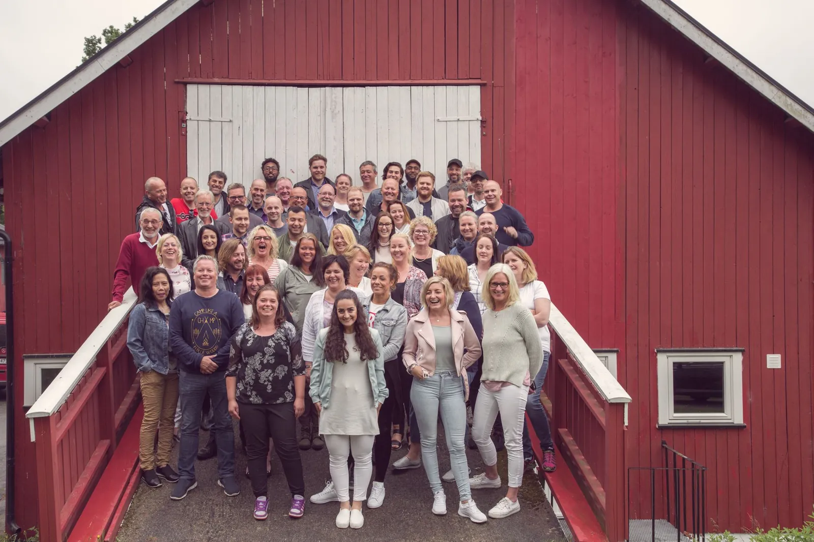 Medarbeidere i Omsorgspartner samlet foran en rød låve