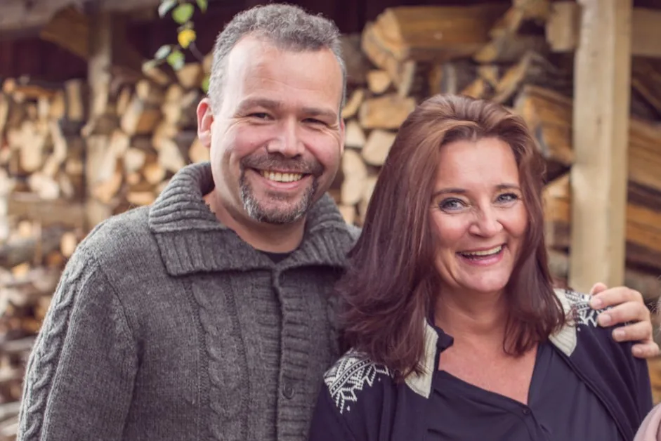 Smilende mann og kvinne foran en vedstabel